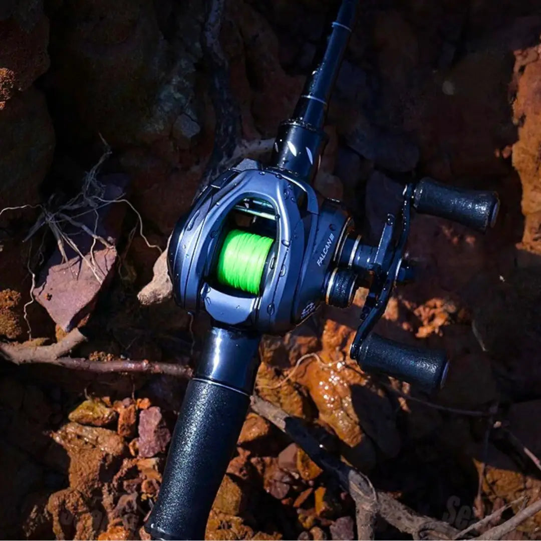 Carretilha SeaKnight FALCAN III com linha verde instalada posicionada sobre pedras molhadas